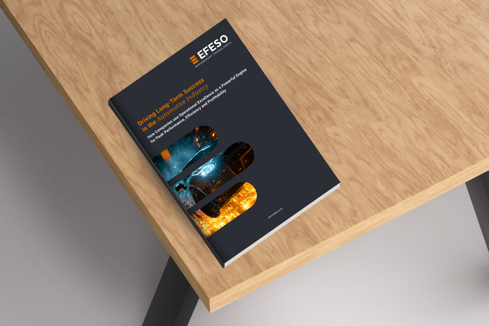A magazine with a dark cover featuring images of a car, industry, and fire sits on a light wooden desk. The title reads Driving Long-Term Success in the Automotive Industry by EFESO. EFESO Management Consultants