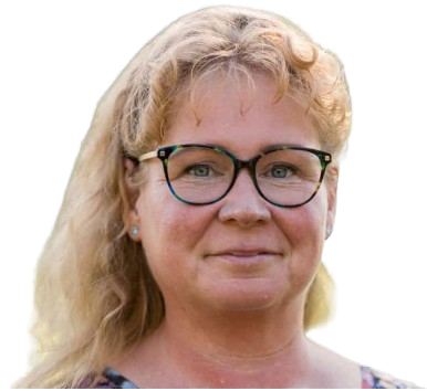 A middle-aged woman with wavy blonde hair and glasses, wearing a patterned top, smiles gently against a plain light background, her eyes reflecting the serenity of a quiet forest. EFESO Management Consultants