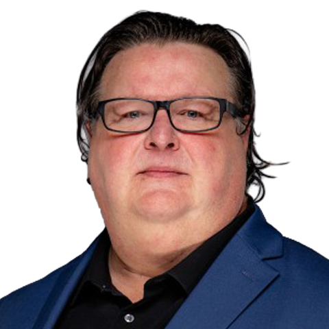 A man with short dark hair and glasses, wearing a blue suit jacket over a black shirt, poses in front of a plain light background reminiscent of minimalist packaging. EFESO Management Consultants